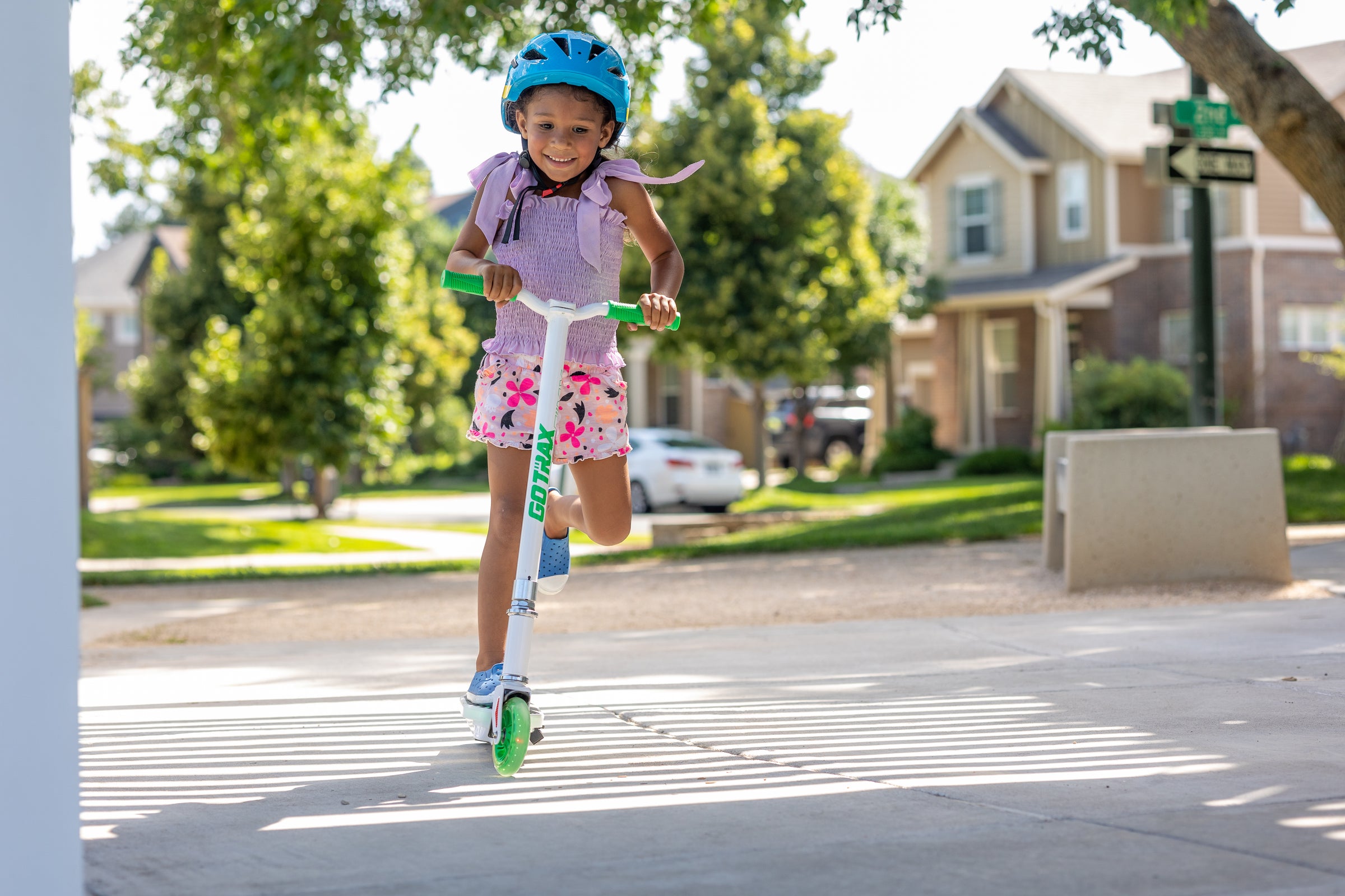 Young Child riding a GOTRAX Green Scout Electric Scooter for Kids with LED Deckboard